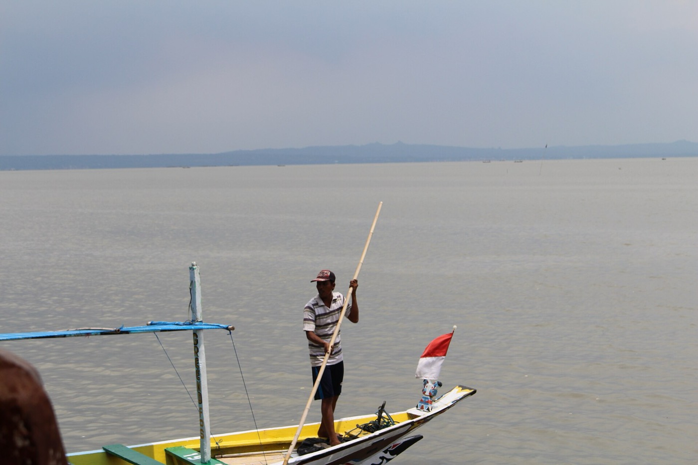 Pantai Kenjeran dengan perahu nelayan di dermaga kecil.