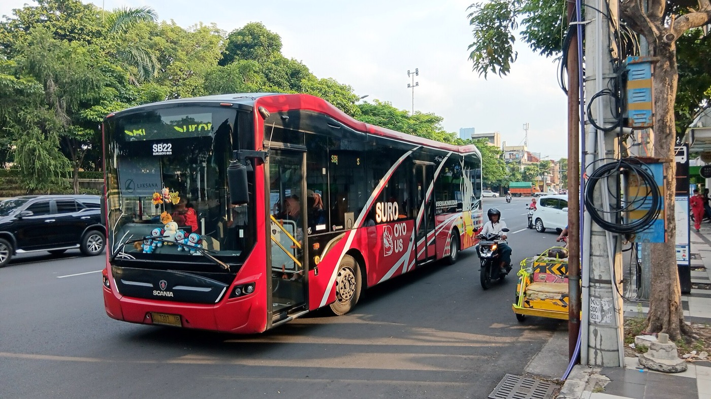 Bus Suroboyo melintas di Jalan Rajawali, penumpang menunggu di halte.